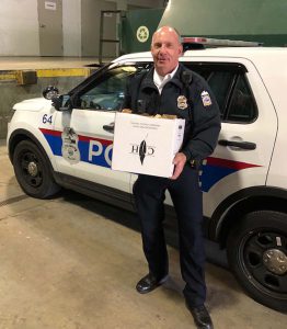 Columbus Police officer standing outside his cruiser holding a box of donated meal delivery from Cooper’s Hawk at Easton.